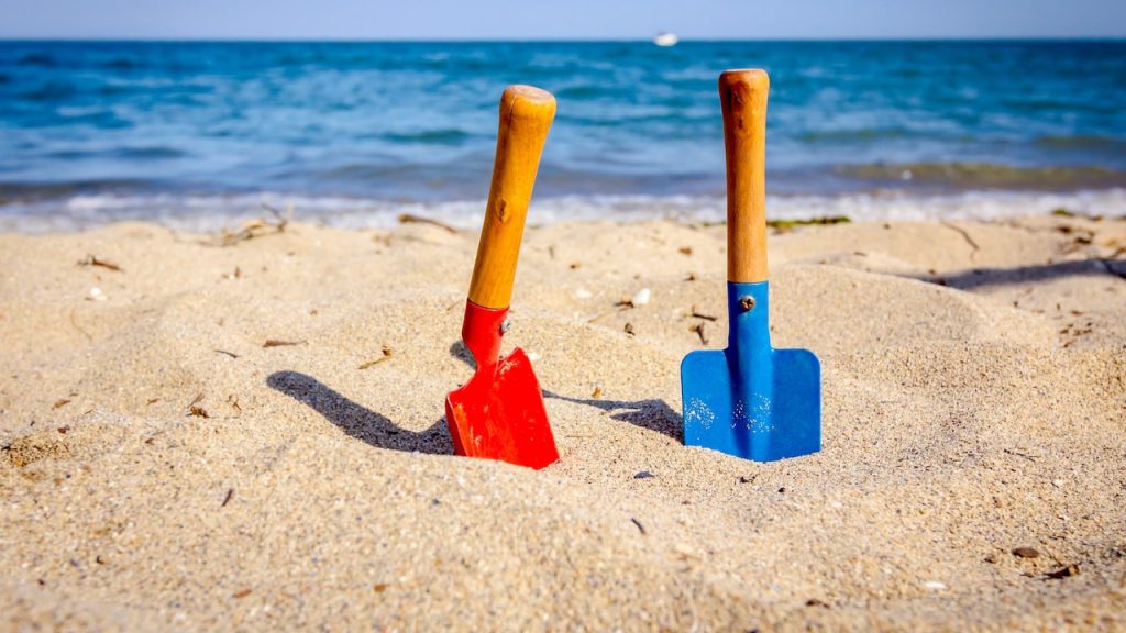 Schaufeln aus Holz und Metall am Sandstrand - nachhaltiges Sandspielzeug